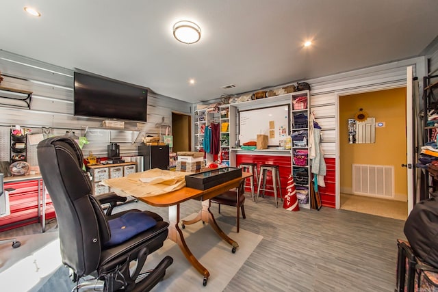 home office featuring wood walls, wood-type flooring, and a workshop area