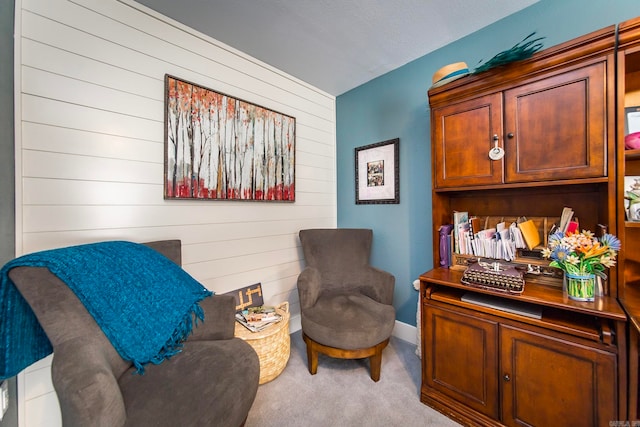 living area featuring light carpet and wooden walls