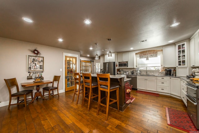 kitchen with a kitchen island, white cabinetry, dark wood-type flooring, and stainless steel appliances