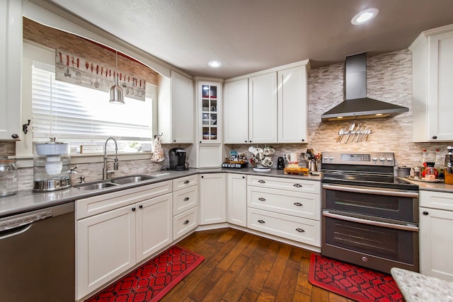 kitchen with wall chimney exhaust hood, white cabinetry, stainless steel appliances, and sink