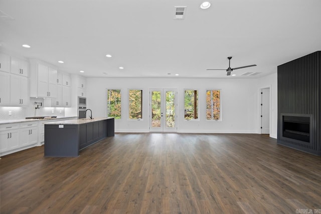 kitchen with a kitchen island with sink, dark hardwood / wood-style floors, white cabinets, and stainless steel appliances