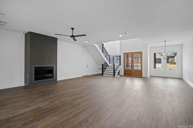 unfurnished living room with dark wood-type flooring and ceiling fan with notable chandelier