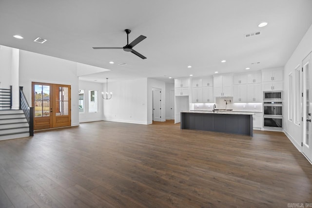 unfurnished living room with sink, ceiling fan with notable chandelier, and dark hardwood / wood-style flooring