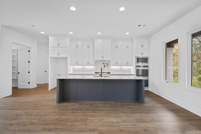 kitchen featuring white cabinetry, stainless steel appliances, dark hardwood / wood-style flooring, and a kitchen island with sink