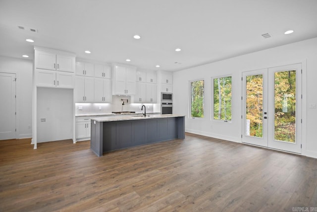 kitchen with a center island with sink, dark hardwood / wood-style flooring, white cabinetry, french doors, and stainless steel appliances