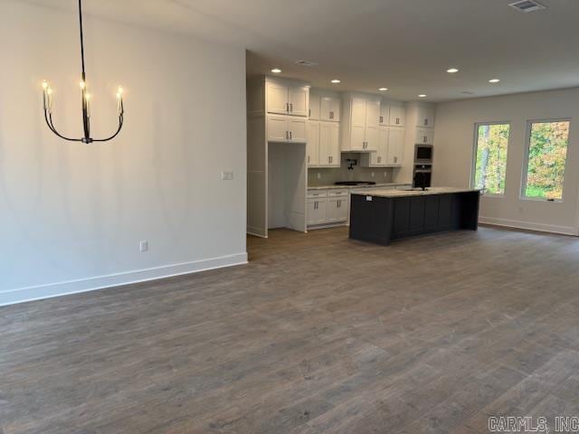 kitchen with a kitchen island with sink, hardwood / wood-style flooring, and white cabinetry