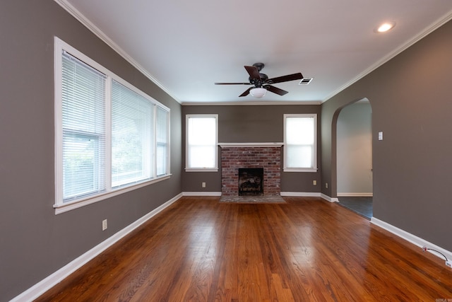 unfurnished living room featuring ceiling fan, ornamental molding, a brick fireplace, and dark hardwood / wood-style floors