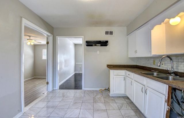 kitchen featuring tasteful backsplash, sink, white cabinetry, ceiling fan, and light hardwood / wood-style flooring