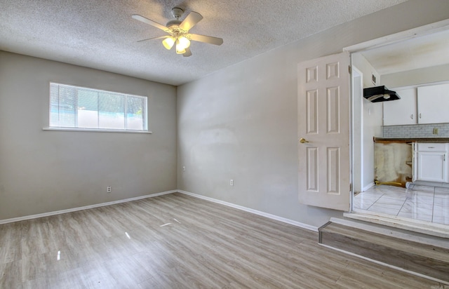 spare room featuring light hardwood / wood-style flooring, a textured ceiling, and ceiling fan