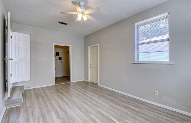 unfurnished room with ceiling fan, a textured ceiling, and light wood-type flooring