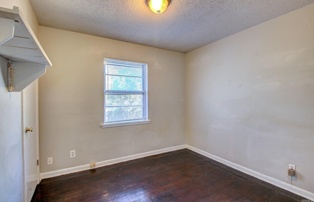 empty room with a textured ceiling and dark wood-type flooring