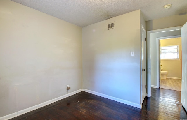 unfurnished room with a textured ceiling and dark wood-type flooring