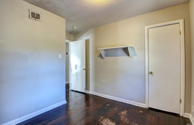 empty room featuring a textured ceiling and dark hardwood / wood-style floors