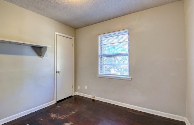 empty room featuring a textured ceiling and dark wood-type flooring