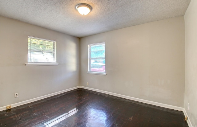 unfurnished room featuring a wealth of natural light, a textured ceiling, and dark hardwood / wood-style floors