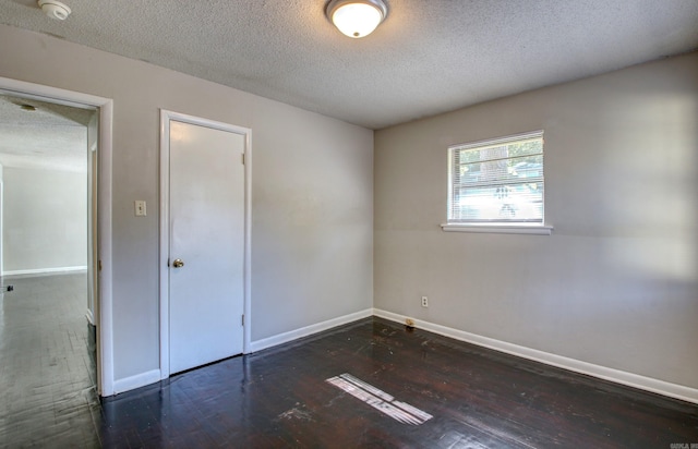 spare room featuring a textured ceiling and dark hardwood / wood-style flooring