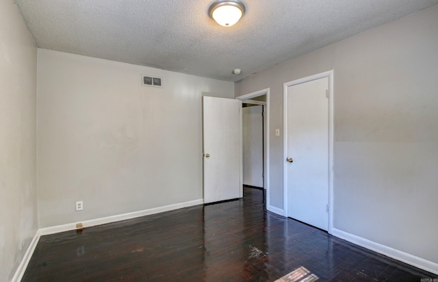 unfurnished room featuring a textured ceiling and dark hardwood / wood-style flooring