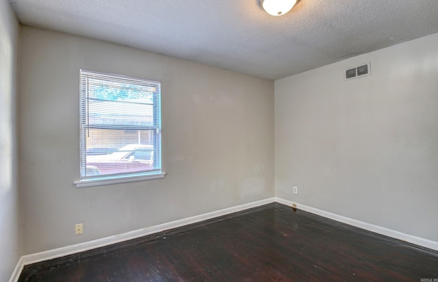 empty room featuring dark hardwood / wood-style floors and a textured ceiling