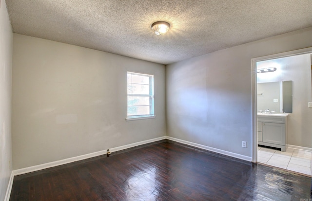 spare room with a textured ceiling and light hardwood / wood-style flooring