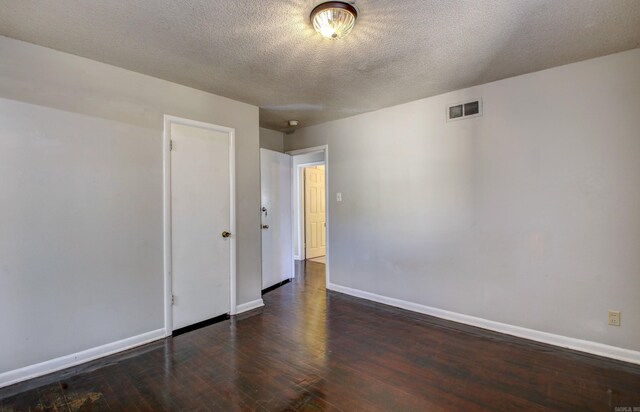 empty room with a textured ceiling and dark hardwood / wood-style floors