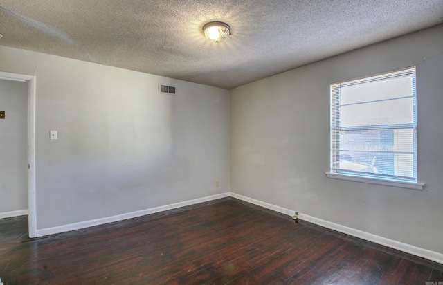 empty room with dark hardwood / wood-style floors and a textured ceiling