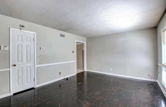 spare room with a textured ceiling and dark hardwood / wood-style flooring