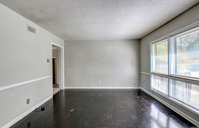 spare room featuring dark wood-type flooring and a textured ceiling