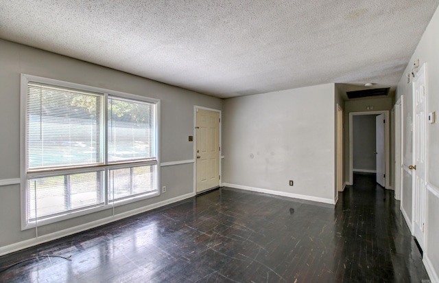 unfurnished room with a textured ceiling and dark hardwood / wood-style flooring