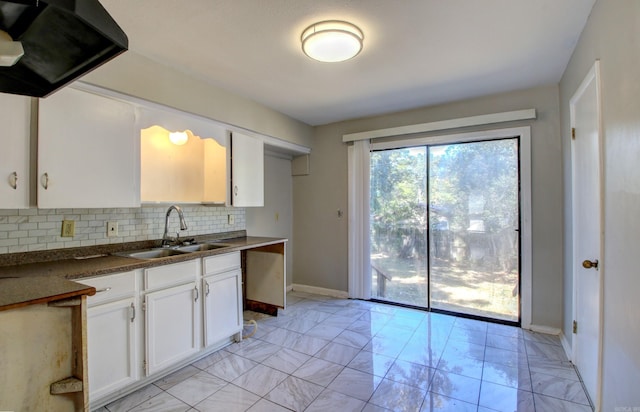 kitchen featuring decorative backsplash, white cabinetry, sink, and exhaust hood