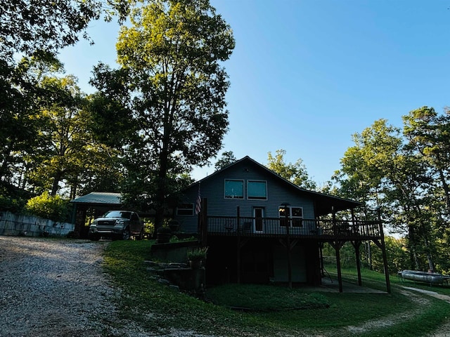 view of property exterior with a wooden deck, a lawn, and a carport