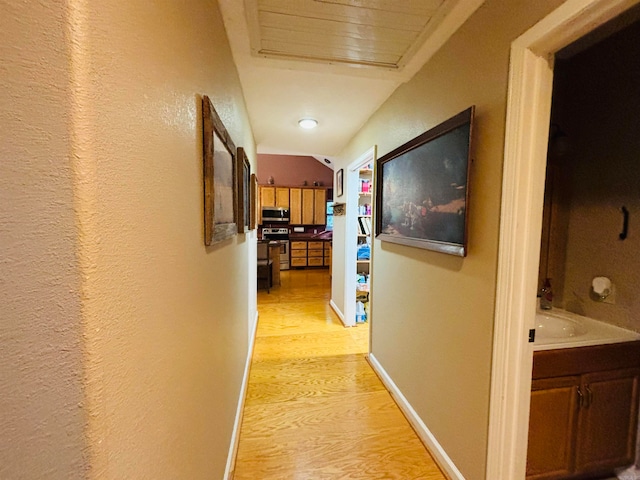 hallway with lofted ceiling and light hardwood / wood-style flooring