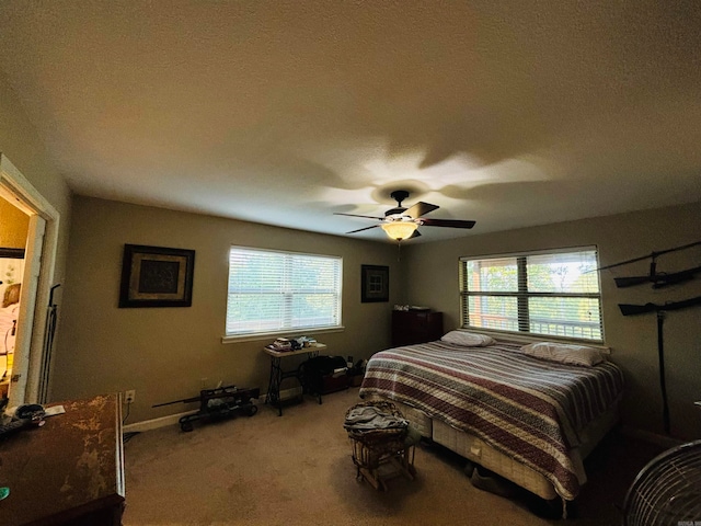 carpeted bedroom with a textured ceiling, multiple windows, and ceiling fan