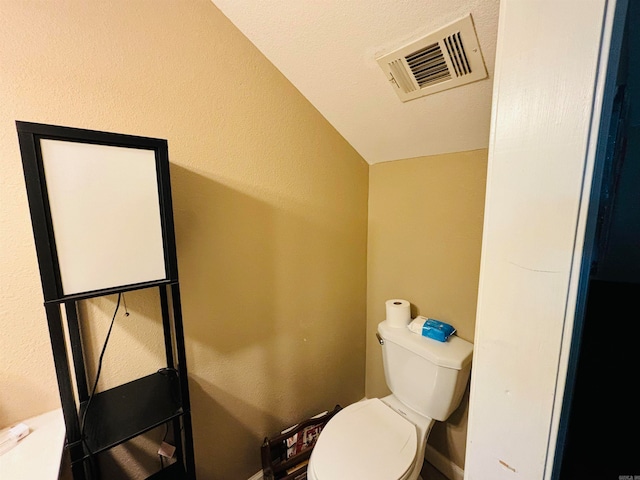 bathroom featuring toilet, a textured ceiling, and vaulted ceiling