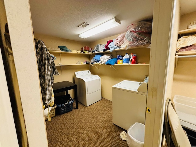 clothes washing area featuring a textured ceiling, washing machine and clothes dryer, and carpet flooring