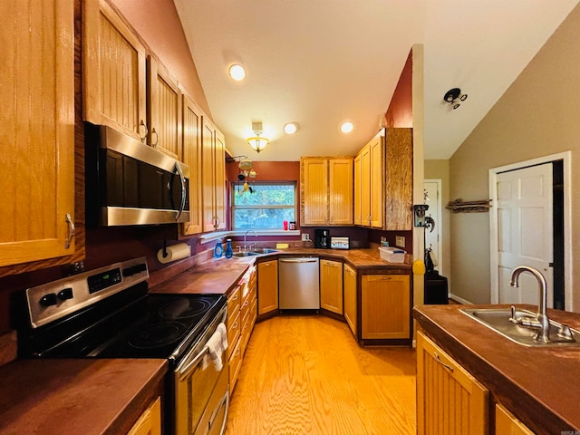 kitchen featuring wooden counters, light hardwood / wood-style flooring, sink, vaulted ceiling, and appliances with stainless steel finishes