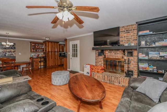 living room featuring ceiling fan, wood-type flooring, ornamental molding, and a fireplace