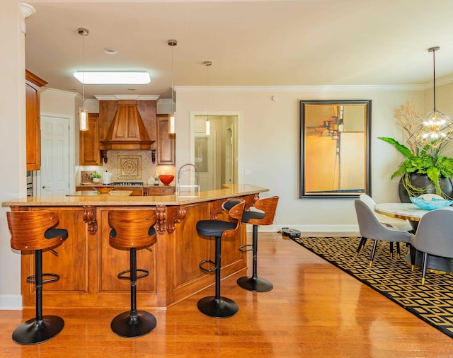 kitchen featuring light stone countertops, a kitchen breakfast bar, hanging light fixtures, ornamental molding, and an inviting chandelier