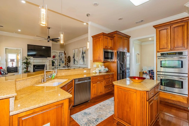 kitchen featuring dark wood-type flooring, sink, crown molding, pendant lighting, and appliances with stainless steel finishes