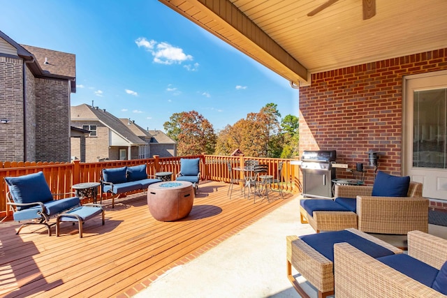 wooden deck featuring area for grilling, an outdoor living space with a fire pit, and ceiling fan