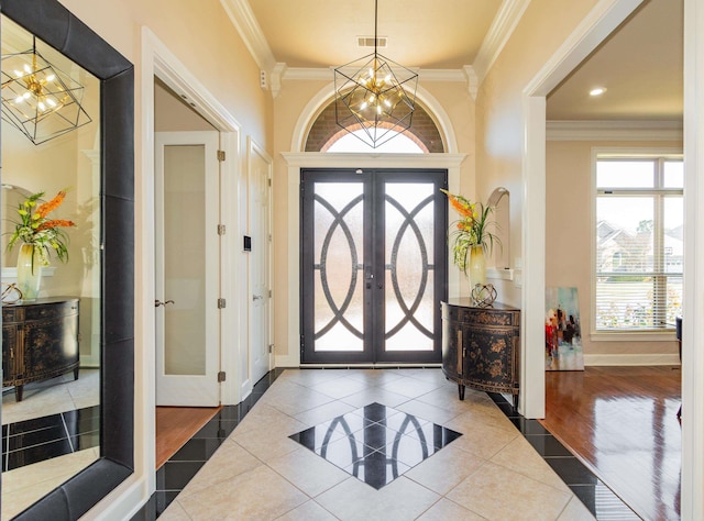 entryway featuring french doors, hardwood / wood-style flooring, ornamental molding, and a chandelier