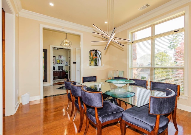 dining area featuring an inviting chandelier, ornamental molding, and wood-type flooring