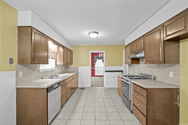 kitchen featuring sink, backsplash, a textured ceiling, stainless steel appliances, and light tile patterned floors