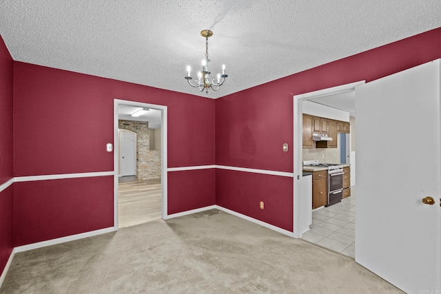 spare room with light carpet, a notable chandelier, and a textured ceiling