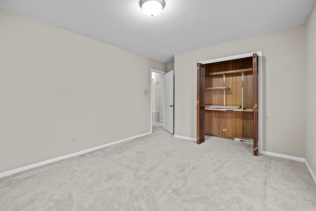 unfurnished bedroom with light carpet, a textured ceiling, and a closet