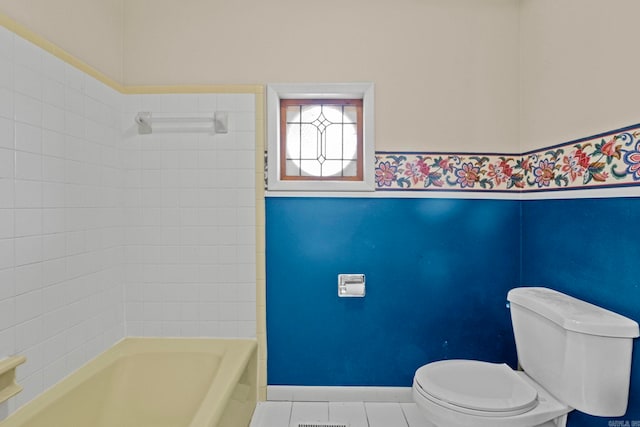 bathroom featuring tile patterned floors, tiled shower / bath combo, and toilet