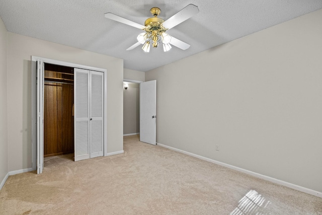 unfurnished bedroom featuring light carpet, a closet, a textured ceiling, and ceiling fan