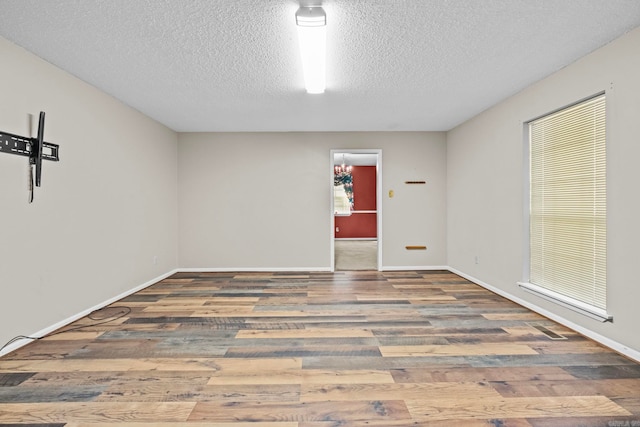 spare room with a healthy amount of sunlight, hardwood / wood-style flooring, and a textured ceiling