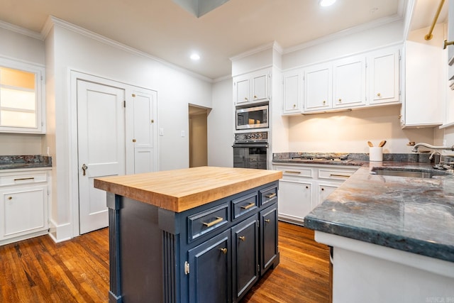 kitchen with appliances with stainless steel finishes, white cabinets, a center island, and dark hardwood / wood-style flooring