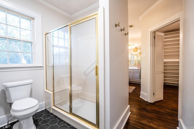 bathroom with hardwood / wood-style flooring, toilet, a shower with shower door, crown molding, and vanity