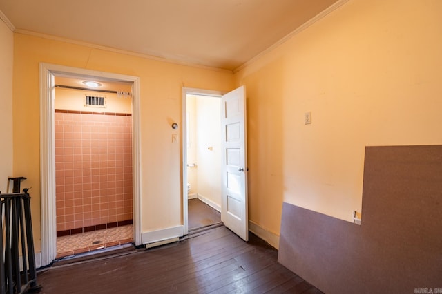 unfurnished bedroom with connected bathroom, ornamental molding, dark hardwood / wood-style floors, and tile walls